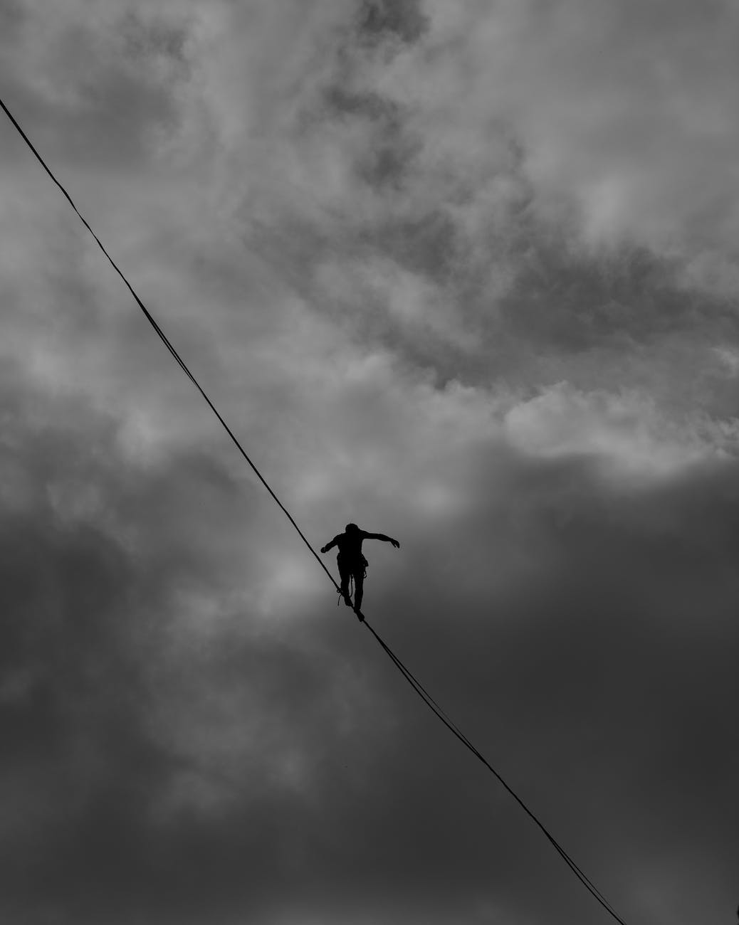 low angle photo grayscale of person tightrope walking